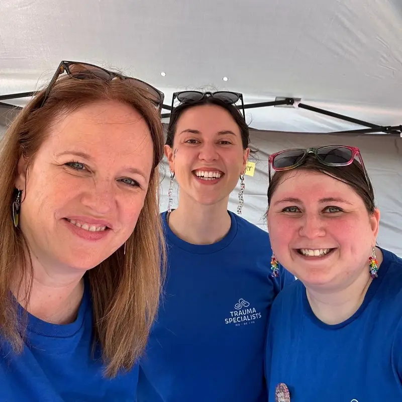 Three Trauma Specialists clinicians smiling together at a community event