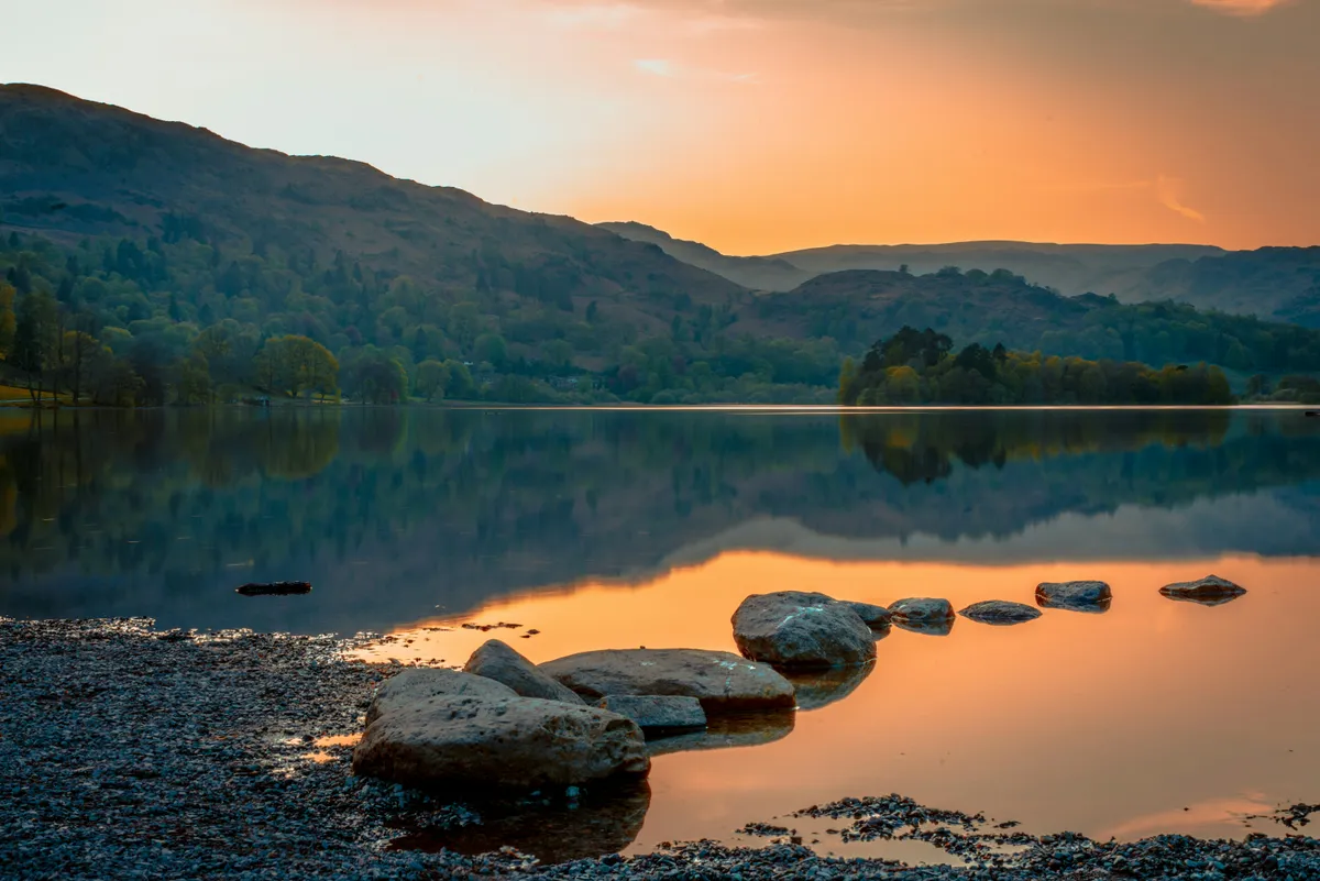 Stepping stones leading across a calm lake at dawn